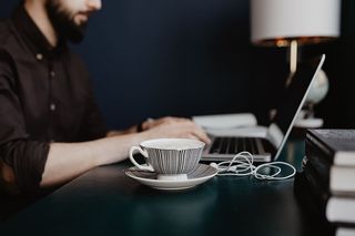 男性用笔记本电脑和一杯咖啡工作