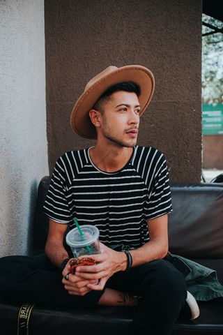 穿着黑白条纹衬衫拿着杯子的男子