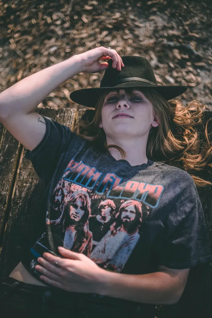 身着灰粉色弗洛伊德衬衫的微笑女子躺在棕色木质表面上