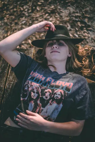 身着灰粉色弗洛伊德衬衫的微笑女子躺在棕色木质表面上