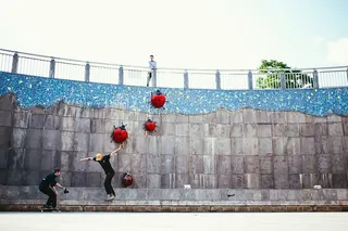 一名旁观者在滑板公园里看着一名滑板运动员被另一名滑板运动员拍照