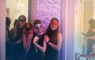 四名戴着口罩的年轻女子在夜总会里拿着酒杯摆姿势