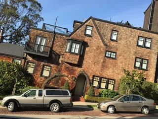 白天，在棕色油漆房子附近，银色旅行车后面的银色轿车