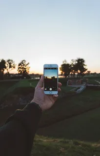 白天手持iPhone白色手机拍照的人 白天手持iPhone白色手机拍照的人