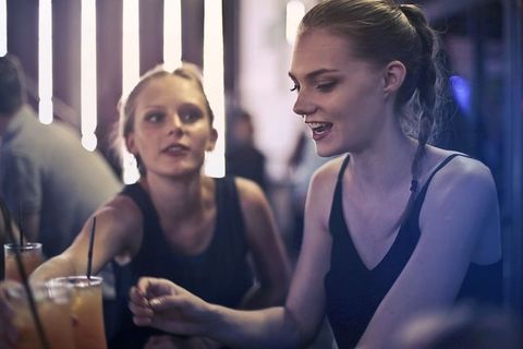 两个年轻的金发女郎坐在酒吧里喝着酒