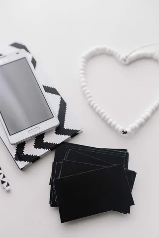 黑白笔记本和带有各种物品的白色智能手机