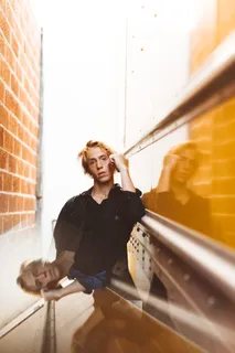 穿着黑色夹克的男人站在棕色砖墙旁边的浅焦点照片 穿着黑色夹克的男人站在棕色砖墙旁边的浅焦点照片