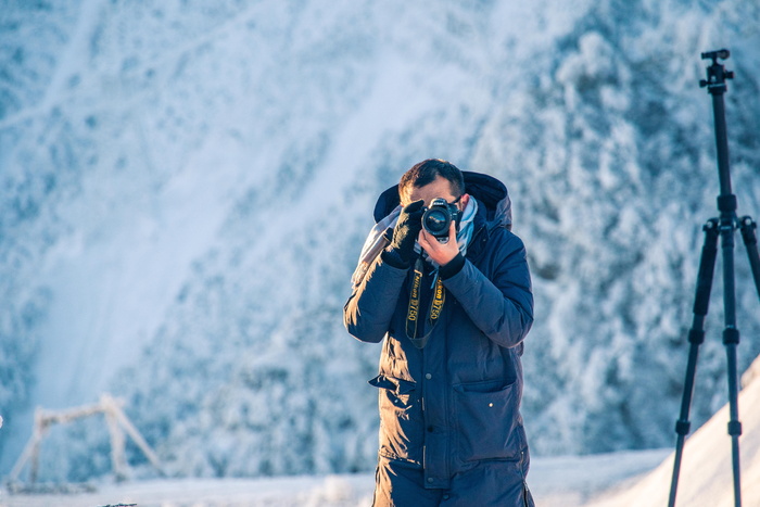 男子身穿黑色连帽衫，手持摄像机
