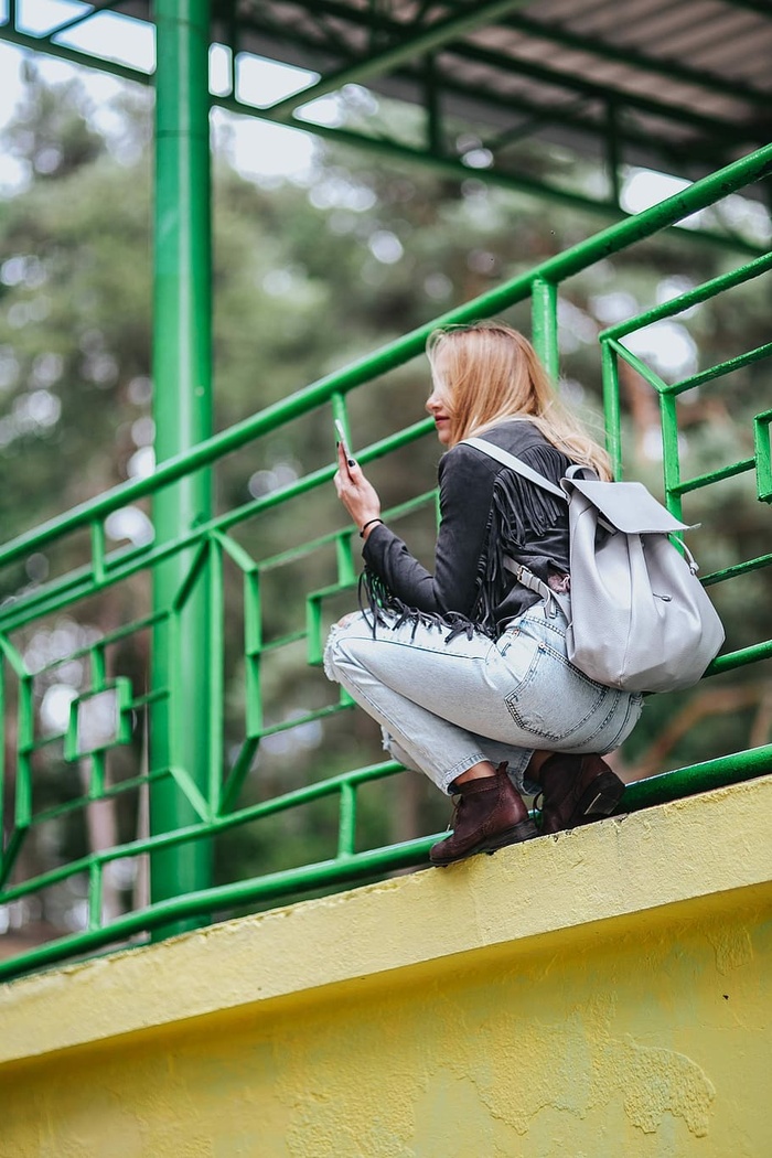 穿着黑色夹克和绿色扶手撕破牛仔裤的金发女人