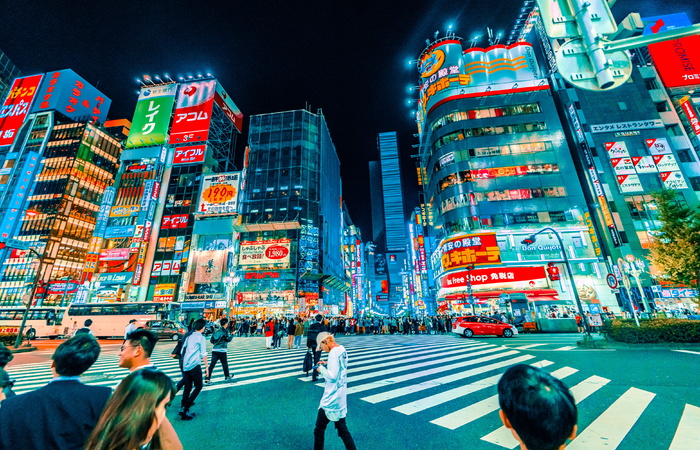 人们在夜间穿过建筑物附近的行人