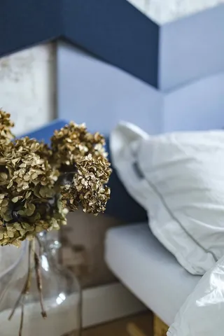 设计师卧室，床边的罐子里放着一株金色的装饰植物