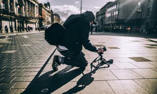 person kneeling on floor taking photo with sunlight