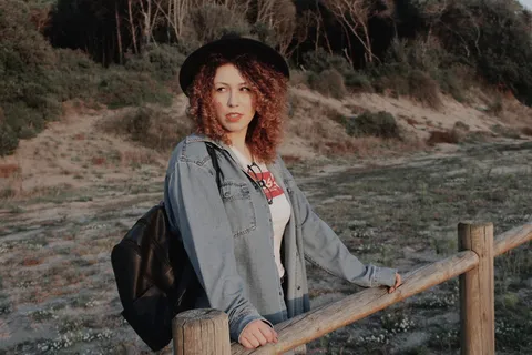 身穿蓝色牛仔夹克、背着黑色皮革背包的女子