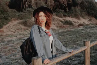 身穿蓝色牛仔夹克、背着黑色皮革背包的女子