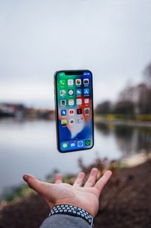 银色iPhone X漂浮在打开的手掌上