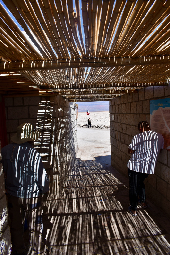 身穿白色圆领衬衫的男子靠在灰色的煤渣砖墙上