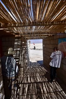 身穿白色圆领衬衫的男子靠在灰色的煤渣砖墙上