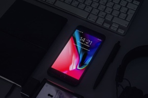 桌子上的钢笔和耳机旁边打开了灰色的iPhone 6