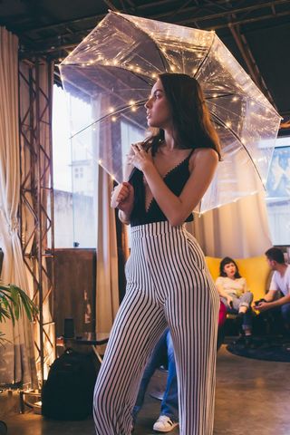 拿着透明雨伞站在建筑物内的女人