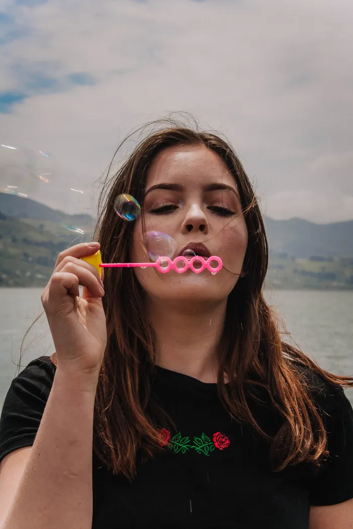 女人用粉色塑料泡泡器吹泡泡