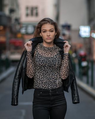 站在路上，一名女子手持黑色夹克