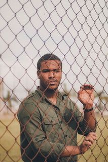 身穿绿色衬衫的男子站在铁丝网围栏后面