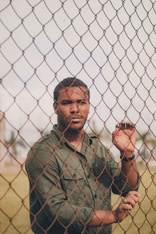 身穿绿色衬衫的男子站在铁丝网围栏后面