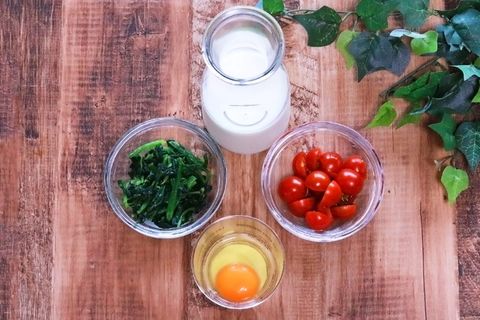 鸡蛋、绿色蔬菜、番茄装在棕色木桌上的玻璃容器中