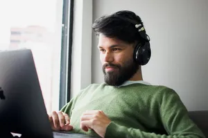戴耳机看MacBook的男子