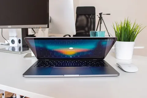 MacBook Pro在白色表面上的Apple Magic鼠标旁打开