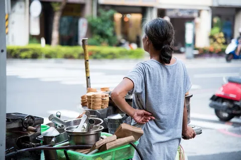 身穿灰色衬衫的女子站在食品车旁边 身穿灰色衬衫的女子站在食品车旁边