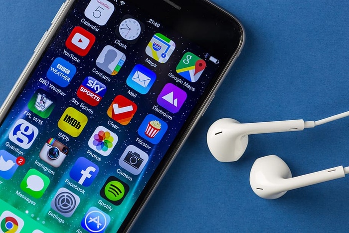 iPhone 6移动智能手机和耳机的特写镜头，背景为纯蓝色
