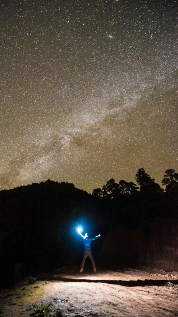 星空下拿照明灯跳起来的人高清摄影图片