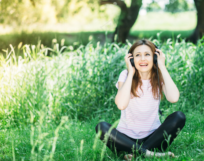坐在草地上听歌的美女图片