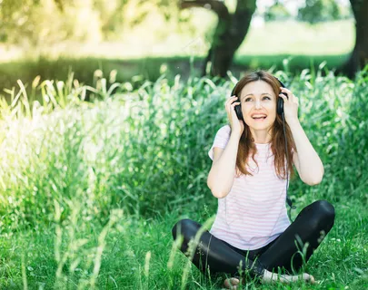 坐在草地上听歌的美女图片