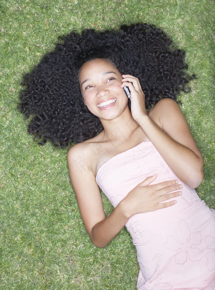 躺在草地上听电话的卷发女生图片