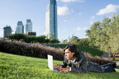 趴在草地上上网的男人图片