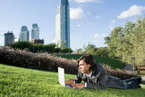 趴在草地上上网的男人图片