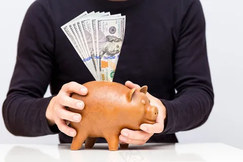 手拿储钱罐金币货币 理财保障商务金融财富增长主题 手拿储钱罐金币货币 理财保障商务金融财富增长主题