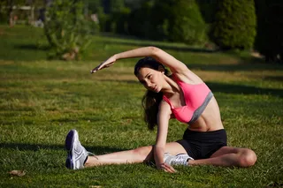 坐在草地上弯腰的美女图片