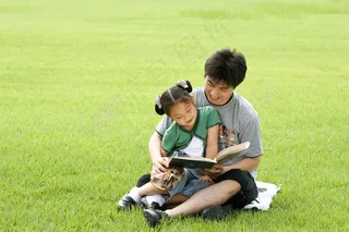 草地上看书的父女图片
