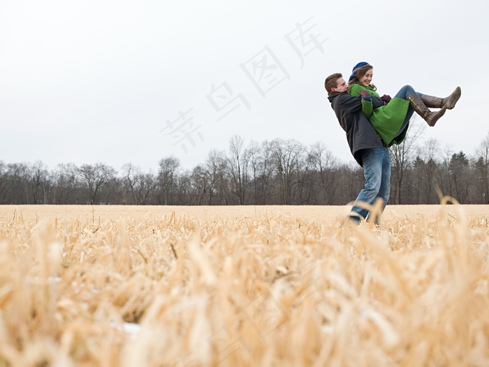 一对幸福恋人在枯萎的草地上嬉戏图片