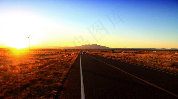 夕阳下公路上行驶的车