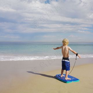 海滩沙滩玩滑板的小帅哥图片