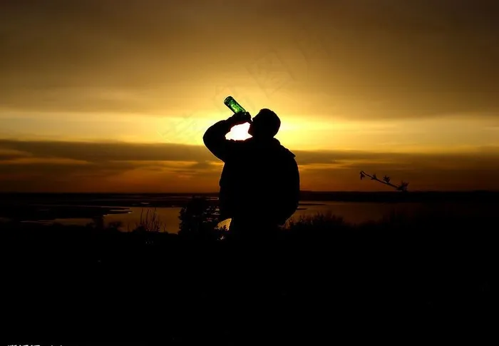 黄昏下海边喝酒的男人图片