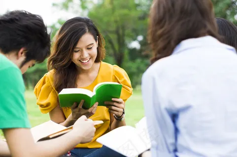 草地上看书的学生图片