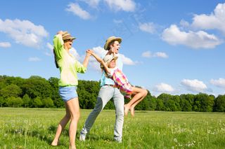 草地上开心跳跃的一家人图片
