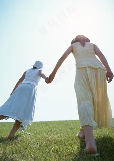 手牵手行走在草地上的女人图片