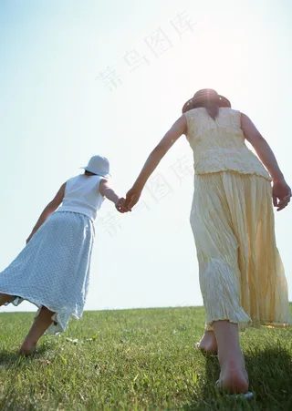 手牵手行走在草地上的女人图片