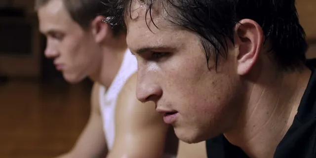 两个汗流浃背的篮球运动员坐在4股的...